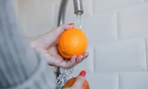 Ręce myją pomarańczę pod bieżącą wodą. Czy pestki pomarańczy są trujące? Nie, są jadalne i zdrowe.