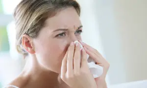 Kobieta z chusteczką przy nosie, szukająca naturalnych sposobów na alergię.