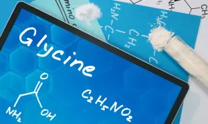 Tablet z napisem "Glycine" i wzorem chemicznym. Obok probówka z białym proszkiem, sugerująca glicyna zastosowanie w chemii.
