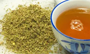 Kopiec suszonego czystka obok filiżanki aromatycznej herbaty. Czystek jest znany ze swoich właściwości.