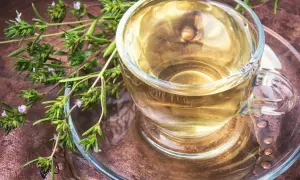 Napar z oregano na płuca, przygotowany ze świeżych ziół, w szklanej filiżance na miedzianym tle.