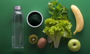 Japońska dieta wodna: butelka wody, spirulina, kiwi, sałata, seler, jabłko i banan na zielonym tle.