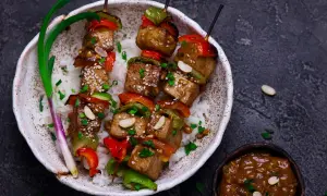 Pyszny grill wegetariański z tofu, papryką i orzeszkami ziemnymi, podany na ryżu.