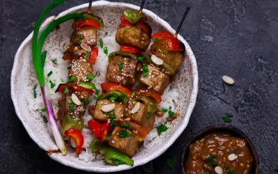 Pyszny grill wegetariański z tofu, papryką i orzeszkami ziemnymi, podany na ryżu.