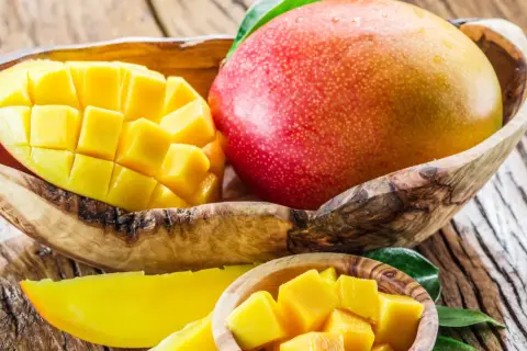 Soczyste mango, pokrojone w kostkę i w całości, w drewnianych miseczkach. To owoc, który jest dobry na wszystko: od orzeźwienia po witaminy.