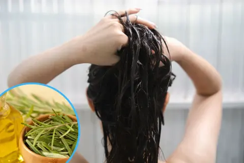 Kobieta wciera w mokre włosy naturalny **napar z rozmarynu na włosy**, obok butelka oleju i miseczka świeżego rozmarynu.