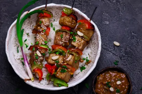 Pyszny grill wegetariański z tofu, papryką i orzeszkami ziemnymi, podany na ryżu.