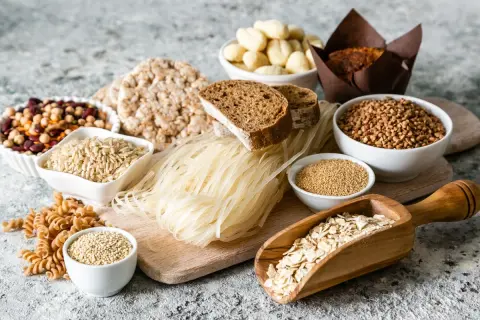 Różnorodne produkty bezglutenowe: ryż, gryka, makaron ryżowy, płatki owsiane, komosa ryżowa, ciecierzyca, fasola, chleb. Czy jęczmień ma gluten? Nie ma go na tym zdjęciu.
