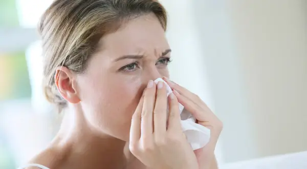 Kobieta z chusteczką przy nosie, szukająca naturalnych sposobów na alergię.