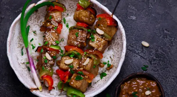 Pyszny grill wegetariański z tofu, papryką i orzeszkami ziemnymi, podany na ryżu.