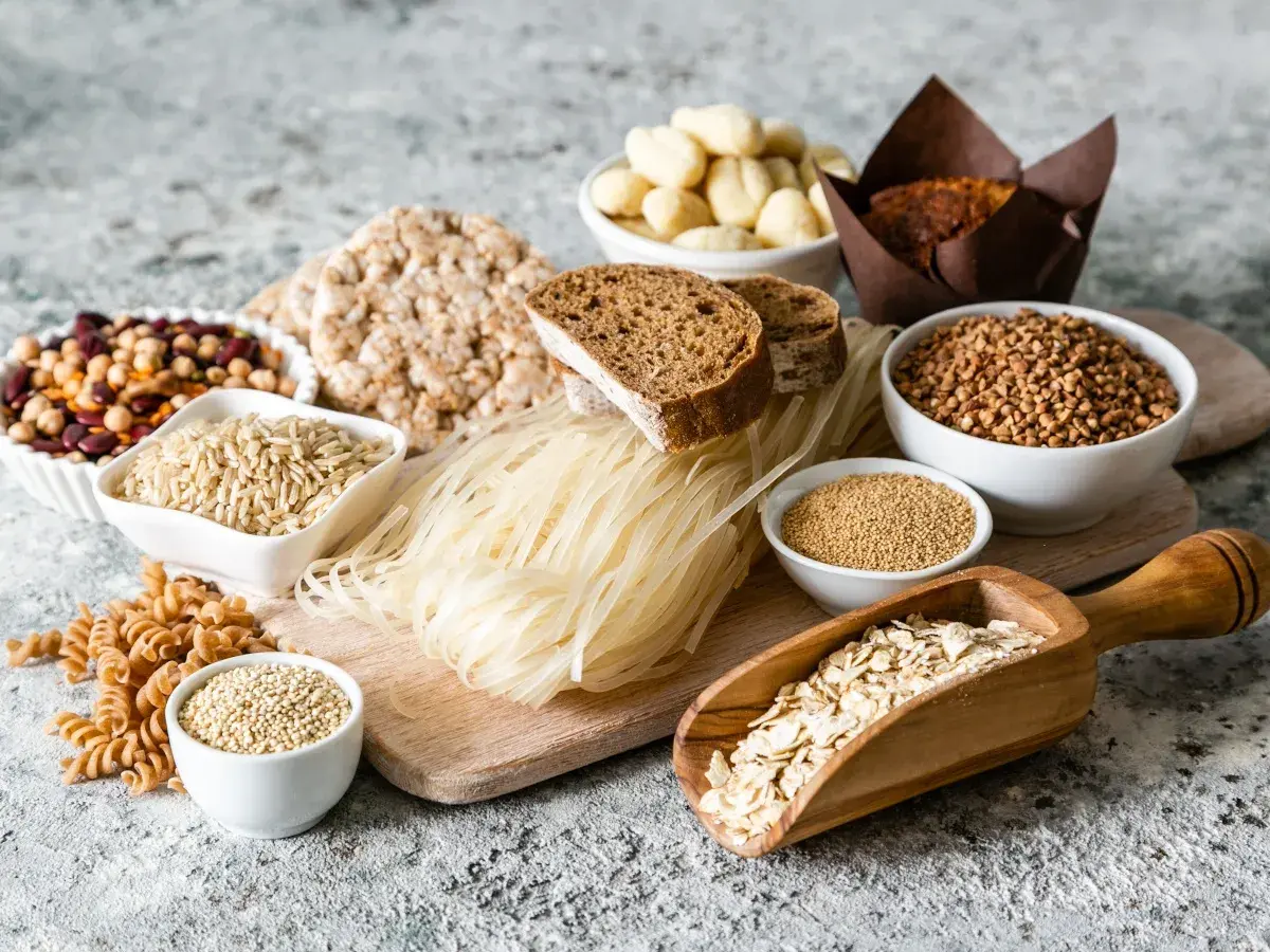Różnorodne produkty bezglutenowe: ryż, gryka, makaron ryżowy, płatki owsiane, komosa ryżowa, ciecierzyca, fasola, chleb. Czy jęczmień ma gluten? Nie ma go na tym zdjęciu.