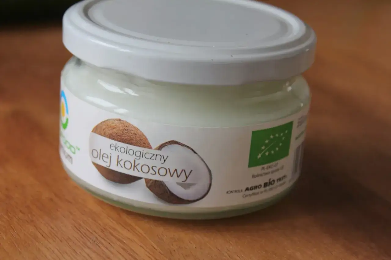 Słoik ekologicznego oleju kokosowego, idealnego do domowej pasty do zęb&oacute;w. Na etykiecie widać kokos i zielone logo UE.